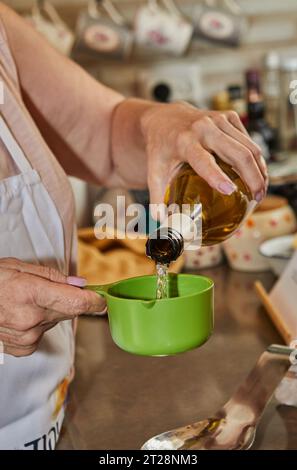 Le chef verse du vin blanc dans une tasse à mesurer Banque D'Images