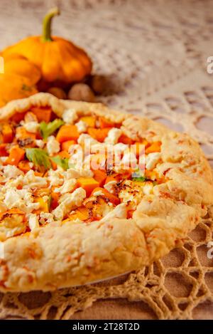 gros plan galette de tarte à la citrouille, tarte ouverte sur nappe tricotée beige sur la table. éclairage chaleureux en soirée Banque D'Images