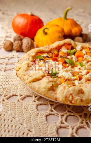 gros plan galette à tarte à la citrouille, tarte ouverte sur une nappe tricotée beige sur la table. éclairage chaleureux en soirée Banque D'Images