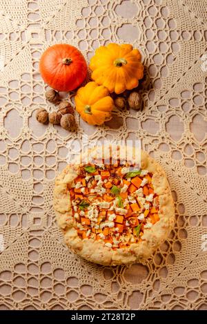 vue de dessus automne nature morte avec récolte - citrouille crue et galette maison, tarte ouverte à la citrouille sur une nappe tricotée beige Banque D'Images