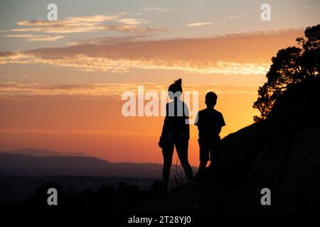 Silhouettes d'une famille monoparentale sur un coucher de soleil dans les montagnes Banque D'Images