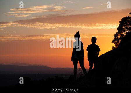 Silhouettes d'une famille monoparentale sur un coucher de soleil dans les montagnes Banque D'Images