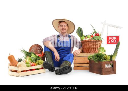 Agriculteur masculin avec des légumes frais et POUR LE signe DE VENTE sur fond blanc Banque D'Images