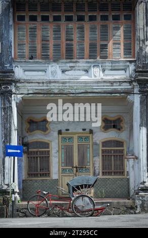 Maison du patrimoine avec vieux trishaw à Penang. Maison vintage de style nanyang. Vieilles maisons abandonnées avec des portes incurvées en bois traditionnelles chinoises. Banque D'Images