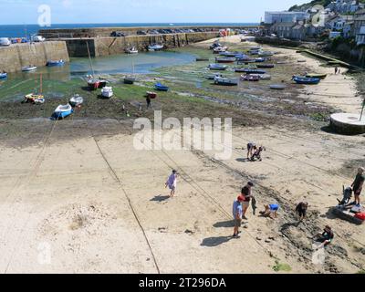 Les bateaux de pêche colorés reposent sur le fond sablonneux en face de la jetée du port de Mousehole en Cornouailles en Angleterre à marée basse Banque D'Images