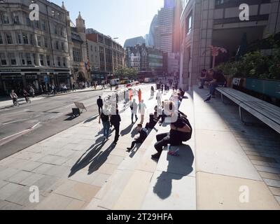 Bishopsgate, au centre de Londres, le 10 octobre 2023, alors que les employés de bureau et les navetteurs profitent du soleil d'automne exceptionnellement chaud. Pendant l'heure du déjeuner, des employés des institutions financières et des entreprises technologiques voisines sont vus assis sur les marches de pierre et les sièges publics des places à côté de Broadgate Banque D'Images
