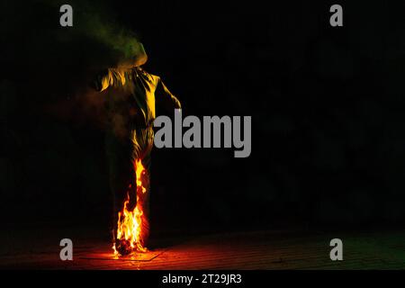 Des flammes brillantes s'élèvent et se déplacent autour de l'épouvantail à la nuit tombée dans un arrière-plan flou Banque D'Images