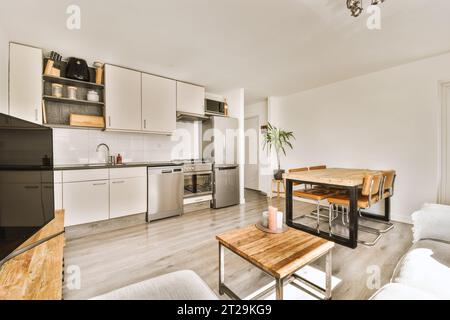 Cuisine ouverte et table à manger avec chaises disposées dans un spacieux appartement contemporain avec des murs blancs Banque D'Images