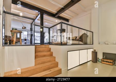 Marches en bois et balustrade en verre menant à un salon élégant dans une maison moderne avec des murs blancs Banque D'Images