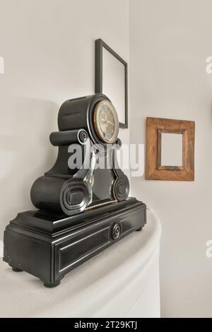 Vintage manteau horloge en bois noir et cadres photo accrochés sur mur blanc dans la maison contemporaine Banque D'Images