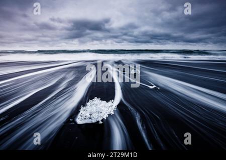 Des morceaux de l'iceberg brillent sur le sable noir. Scène magique et magnifique. Emplacement célèbre place Jokulsarlon lagune, parc national Vatnajokull, Islandais Banque D'Images