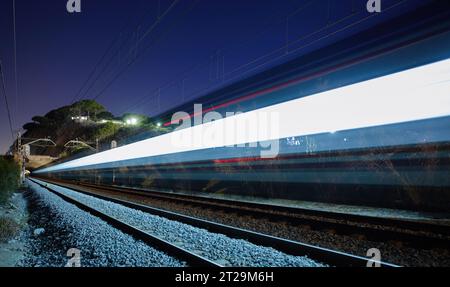 Vue spectaculaire des lumières colorées de train rapide sur le mouvement sur des rails sous le ciel étoilé de nuit Banque D'Images