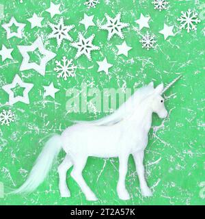 Décoration magique fantaisie licorne de Noël avec flocon de neige et décorations d'étoiles sur fond vert tacheté. Design festif de joyeuses fêtes pour Yule. Banque D'Images