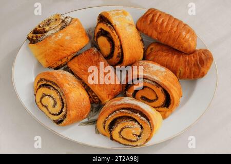 Brioches avec des graines de pavot sur une assiette sur un fond blanc. Brioche maison sucrée. Vue de dessus. Banque D'Images