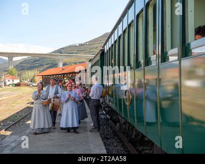 Les gens en vêtements traditionnels chantent à côté du train historique du Douro qui circule entre Régua et Tua en suivant le fleuve Douro, Portugal, Europe Banque D'Images