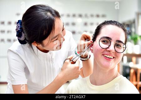 (231018) -- JINAN, 18 octobre 2023 (Xinhua) -- un étudiant slovaque du College of International Exchange de l'Université des sciences et technologies du Shandong fait l'expérience d'une thérapie de médecine traditionnelle chinoise sur les oreilles dans un hôpital de médecine traditionnelle chinoise de la nouvelle région de Xihai'an (côte ouest) à Qingdao, dans la province du Shandong, dans l'est de la Chine, le 18 octobre 2023. L’hôpital, en coopération avec le Collège des échanges internationaux de l’Université des sciences et technologies du Shandong, a invité des étudiants internationaux des pays partenaires de l’Initiative ceinture et route (BRI) à découvrir le charme du tradiol Banque D'Images