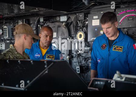 L'équipage d'Artemis II visite la base navale de San Diego. L.T. j.g Thomas Lampognana, à gauche, explique la console de contrôle de barre du navire amphibie de transport à quai USS John P. Murtha (LPD 26) à l’astronaute de la NASA, le capitaine Victor Glover, et à l’astronaute de l’Agence spatiale canadienne Jeremy Hansen, le 19 juillet 2023. La barre est utilisée comme direction principale pour le navire en route. En préparation de la mission Artemis II de la NASA, qui enverra quatre astronautes à Orion au-delà de la Lune, la NASA et la marine américaine effectueront une série de tests pour démontrer et évaluer les processus, les procédures et le matériel utilisés dans les opérations de récupération Banque D'Images