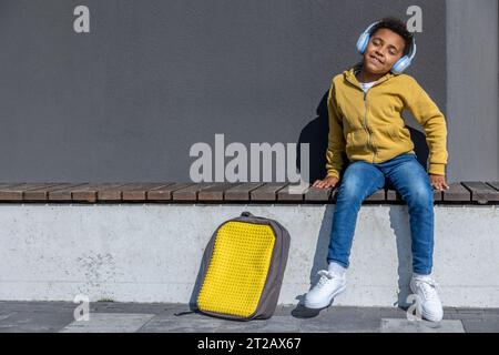 Mignon écolier dans un casque écoutant de la musique et regardant apprécié Banque D'Images
