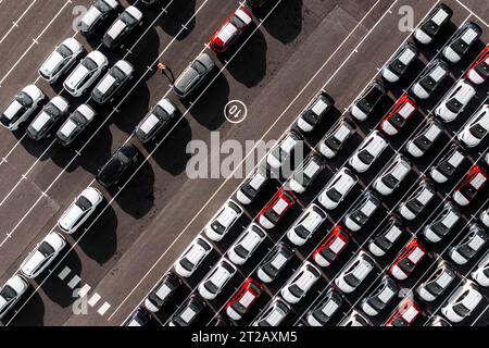 Vue aérienne directement au-dessus des rangées de voitures nouvellement construites dans l'industrie automobile sur un quai commercial prêt à être chargé pour les droits d'exportation et d'importation Banque D'Images