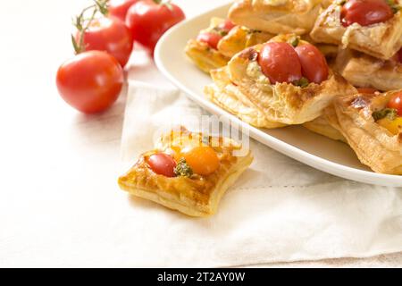 En-cas feuilletés cuits au four avec fromage à la crème, tomates et pesto aux herbes, amuse-gueules servis sur une serviette blanche et une assiette dans un buffet froid, spa copie Banque D'Images