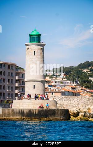 Les gens se détendent au pied du phare de Cassis qui se dresse à l'embouchure du port de Cassis, dans le sud de la France. Banque D'Images