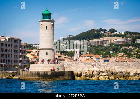 Les gens se détendent au pied du phare de Cassis qui se dresse à l'embouchure du port de Cassis, dans le sud de la France. Banque D'Images