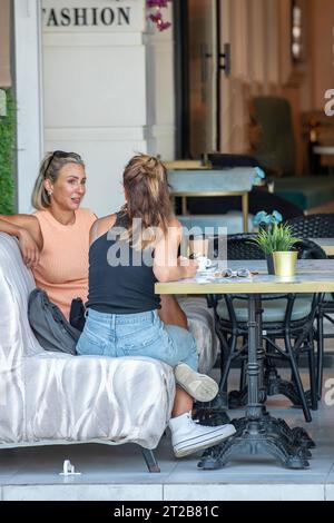 deux jeunes femmes bavardent autour d'un café dans un restaurant de rue ou un café sur l'île grecque de zante ou zakynthos Banque D'Images