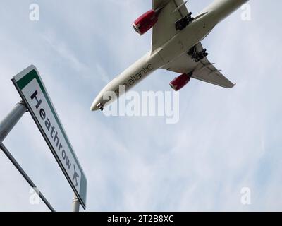 Aéroport de Londres Heathrow Hounslow, panneau routier pour l'aéroport d'Heathrow avec Virgin Atlantic Airbus A350-1041 volant à basse altitude au-dessus du ciel bleu Banque D'Images