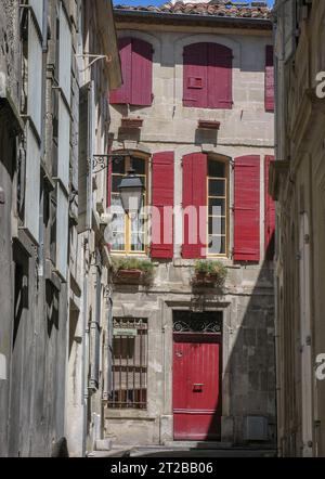 Volets rouges recouvrant les fenêtres d'un mur à Arles. Banque D'Images