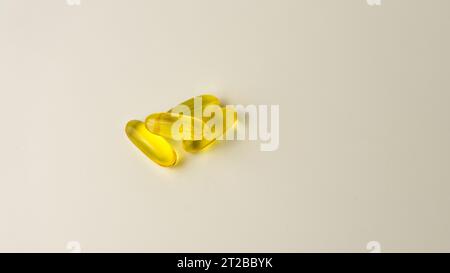 Capsules de saumon sauvage et d'huile de poisson riches en oméga-3 présentées sur un fond blanc cassé doux. Banque D'Images