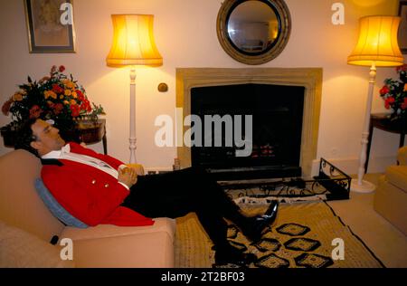 Fatigué épuisé toute la nuit en prenant le repos facile loin de la piste de danse bondée. Un maître des Foxhounds en veste rose de chasse traditionnelle. Hunt ball au Tysoe Manor, célèbre la fin de la saison de chasse. Tysoe, Warwickshire, Angleterre avril 1982. ANNÉES 1980 ROYAUME-UNI HOMER SYKES. Banque D'Images