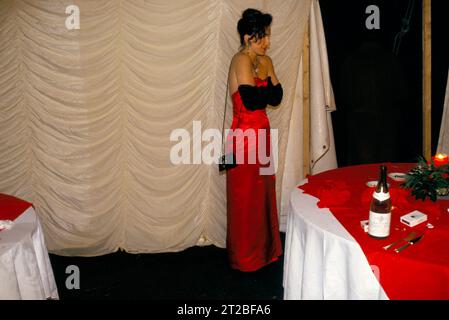 Seul froid une jeune femme dans une robe de bal rouge sans bretelles sur l'épaule, portant de longs gants de soirée formels noirs. S'embrasse pour essayer de se tenir au chaud, elle attend son partenaire. Hunt ball au Tysoe Manor, Tysoe, Warwickshire, Angleterre le 1982 avril. ANNÉES 1980 ROYAUME-UNI HOMER SYKES. Banque D'Images