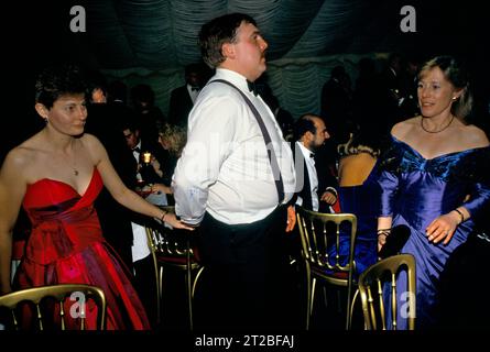 Sans bretelles sur les robes de balle d'épaule. Années 1980 Royaume-Uni. Homme conduisant une femme sur la piste de danse, elle tient sa main en étant conduit. Dîner danse, formel, il est chaud et a enlevé sa veste. Hunt ball au Tysoe Manor, Tysoe, Warwickshire, Angleterre le 1982 avril. ANNÉES 1980 ROYAUME-UNI HOMER SYKES. Banque D'Images