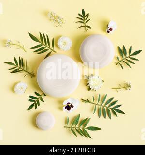 Piédestal de podium rond en bois présentation cosmétique de produit de beauté maquette vide sur fond pastel vert avec des feuilles et des fleurs blanches. Minimaliste fl Banque D'Images