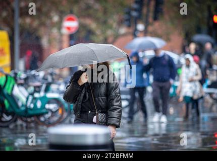 Londres, Royaume-Uni. 18 octobre 2023. UK Weather.Kings Cross, Londres, Royaume-Uni. Le temps humide venteux fait d'un parapluie ou d'un brolly un accessoire essentiel pour les travailleurs et les acheteurs autour de Kings Cross, Londres, Royaume-Uni, mercredi après-midi avant Storm Babet. Crédit : Windmill Images/Alamy Live News Banque D'Images