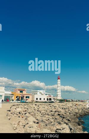 Phare, quelques maisons et la plage de Ilha do Farol, île barrière de Culatra, Olhao, Algarve, Portugal Banque D'Images