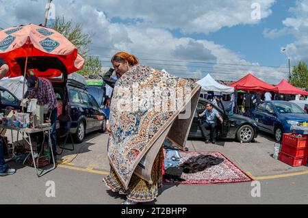 Octobre 5 -2023- Bucarest Roumanie- marché aux puces où vous pouvez trouver pratiquement n'importe quoi à des prix très bas. Une femme veut vendre un tapis et porte Banque D'Images