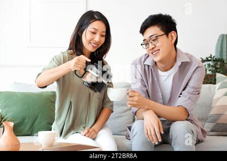 Jeune femme asiatique versant le café dans la tasse de son amie à la maison Banque D'Images