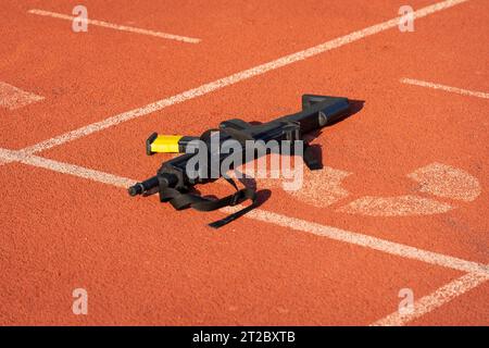 Armes d'entraînement noires sur la ligne de départ pointillée d'une piste de course orange Banque D'Images