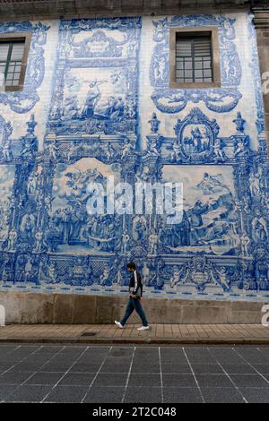 Homme marchant devant les tuiles Capela das Almas Azulejo à Porto, Portugal Banque D'Images