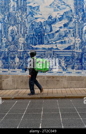 Homme marchant devant les tuiles Capela das Almas Azulejo à Porto, Portugal Banque D'Images