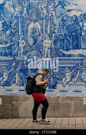 Homme marchant devant les tuiles Capela das Almas Azulejo à Porto, Portugal Banque D'Images