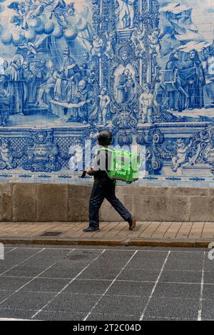 Livreur de nourriture marchant devant les carreaux Capela das Almas Azulejo à Porto, Portugal Banque D'Images