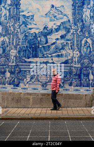 Homme marchant devant les tuiles Capela das Almas Azulejo à Porto, Portugal Banque D'Images