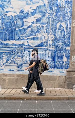 Homme marchant devant les tuiles Capela das Almas Azulejo à Porto, Portugal Banque D'Images