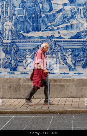 Homme âgé passant devant les carreaux Capela das Almas Azulejo à Porto, Portugal Banque D'Images