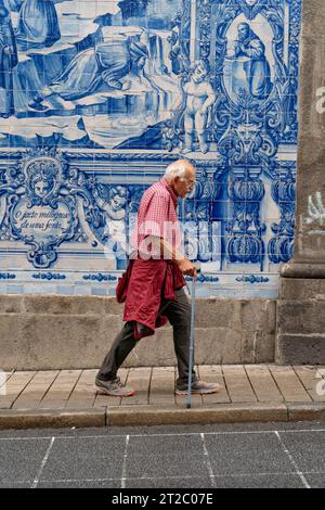 Homme âgé passant devant les carreaux Capela das Almas Azulejo à Porto, Portugal Banque D'Images