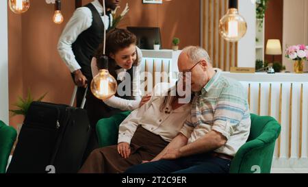 Vieux couple dormant l'un sur l'autre dans le hall de l'hôtel, attendant de voir la réservation de la chambre et commencer les vacances. Les retraités qui font face au décalage horaire après un vol international, se sentent épuisés dans le salon. Banque D'Images