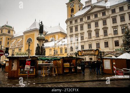 Le plus ancien marché de Noël sur Freyung à Vienne, en Autriche et le monastère Schottenstift avec la statue Austriabrunnen. Banque D'Images