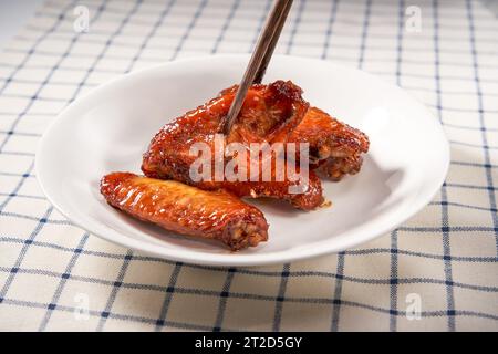 Une assiette d'ailes de poulet grillées dorées et alléchantes au miel Banque D'Images